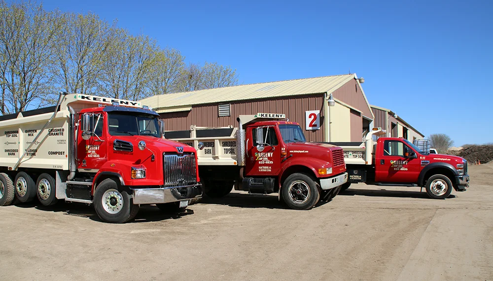 Three red dirt hauling trucks with promotional information for keleny top soil showing granite, rock, soil, mulch, and dirt delivery